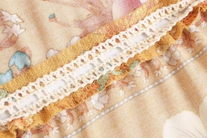 Close-up of mustard floral fabric with elegant white crochet lace stitching detail