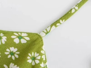 Close-up of fine stitching on thin shoulder straps with green daisy floral print