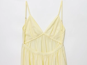 Detail of pale yellow midi dress featuring V-neckline and waist cutout design