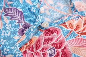 Detailed macro view of the floral print pattern and white button on the shirt neckline