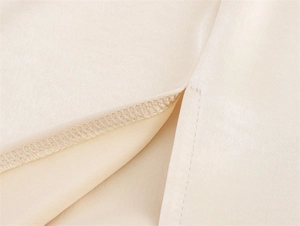 Macro detail of overlock stitching and smooth apricot fabric on a split skirt