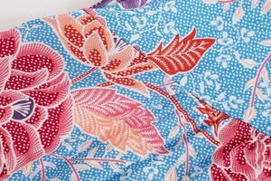 Detailed macro view of vibrant floral print fabric on a blue polka dot background