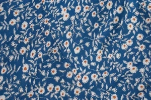 Detailaufnahme von dunkelblauem Blumenstoff mit weißen und orangefarbenen Motiven