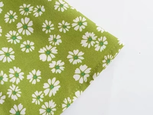 Close-up of green daisy print fabric with clean stitching on sleeveless summer dress