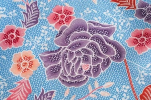 Gros plan détaillé du tissu à fleurs batik bleu avec fleurs violettes et pois blancs