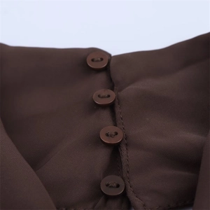 Detailed close-up of four brown buttons on a dark brown ribbed fabric dress
