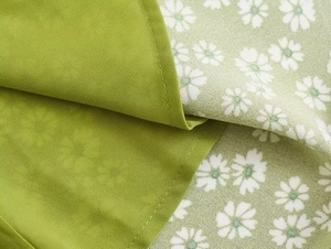 Macro detail of green fabric with daisy print and fine stitching on the summer dress