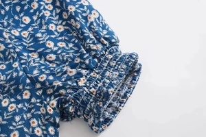 Detailaufnahme der geblümten Ärmel mit elastischen Rüschenbündchen und orangefarbenen Akzenten