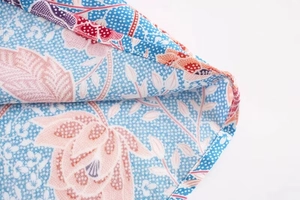 Close-up of bohemian floral print on viscose fabric with detailed rolled hem stitching