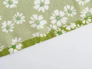 Macro view of light green fabric with white daisy floral print and neat hem stitching