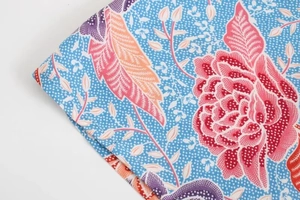Détail de tissu à motif batik floral avec fleurs roses et orange sur fond bleu clair