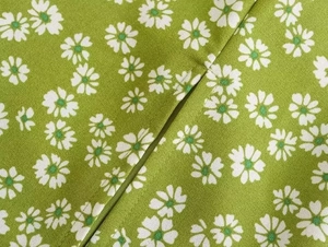 Detailed close-up of green daisy floral print fabric with high-quality stitching detail