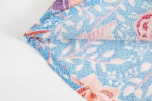 Détail de la couture d'ourlet roulé sur tissu en rayonne à imprimé floral rose