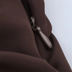 Detail of invisible back zipper closure on dark brown backless halter maxi dress