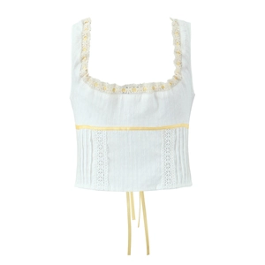 Detail of white jacquard camisole featuring delicate lace trim and yellow ribbon accents