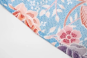 Gros plan sur l'ourlet précis d'une robe en rayonne à imprimé floral et pois bleus