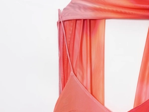 Détail d'une robe en maille dégradée rose et orange avec fines bretelles et coutures précises