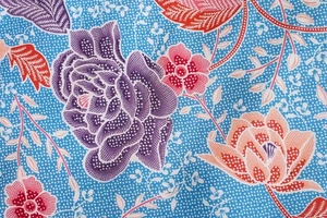 Detailed close-up of blue floral batik fabric with purple roses and intricate white dots