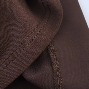 Detail shot showing double-needle stitching and hem on dark brown knitted fabric