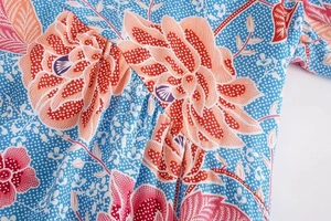Detail of floral print on light blue fabric with white dots and orange blossoms