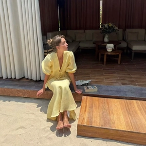 French style pale yellow puff sleeve midi dress with V-neck and tie detail on a terrace