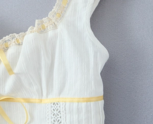 Detail of white embroidered fabric with floral textures and yellow satin ribbon accents