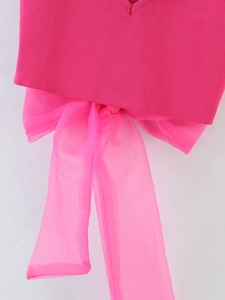 Detail of pink knitted V-neck top featuring a large organza bow and soft texture