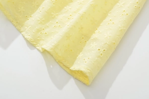 Macro d'un tissu en coton jaune clair avec détails de broderie anglaise à fleurs