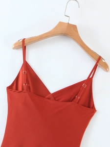 Dettaglio dell'abito sottoveste in raso con spalline regolabili e tessuto lucido rosso-arancio