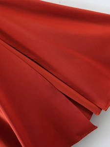 Dettaglio macro dell'abito in raso rosso con cuciture doppie rinforzate e bordo dello spacco