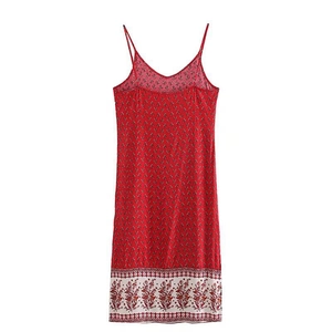 Detailed close-up of a red slip dress featuring ethnic prints and white floral border detail