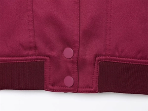 Detailansicht der weinroten Jacke mit Stoffstruktur, Druckknöpfen und geripptem Saum