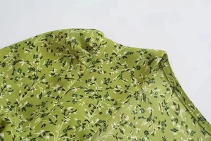 Detailed close-up of green floral dress fabric with reinforced stitching and seam detail