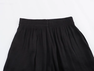 Close-up of wide elastic waistband and ruched detail on black wide-leg trousers