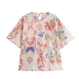 Detail of bohemian floral print on white short sleeve top with back tie-up neck closure