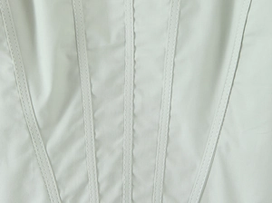 Vue macro des coutures à la taille et de la texture du sergé sur la robe vert clair