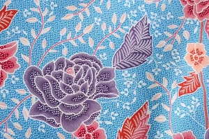 Macro shot of blue floral fabric with purple flowers and detailed batik pattern