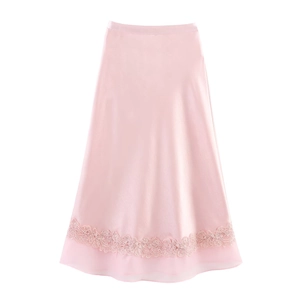 Detailed close-up of light pink satin skirt with delicate floral lace and sheer tulle hem
