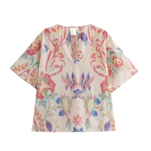 Detail of bohemian floral print on cream short-sleeve shirt with V-neckline ties