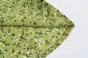 Detail view of green floral dress fabric featuring clean stitching and chiffon texture