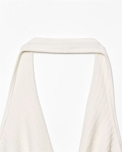 Detailed close-up of white halter neck top with unique wave-textured fabric and deep V-neckline