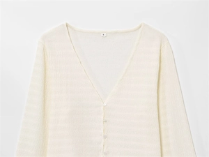 Détail du cardigan blanc crème à col en V avec maille texturée et boutons assortis