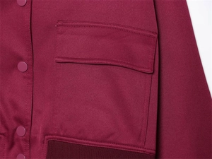 Detailansicht der burgunderroten Jacke mit Pattentaschen, Druckknöpfen und Rippbündchen