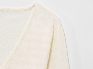 Gros plan du col en V avec texture plissée verticale sur un haut pour femme couleur crème