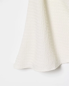 Detailed macro view of white top fabric with three-dimensional wavy seersucker texture