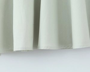 Gros plan détaillé sur la texture du tissu vert menthe et les coutures de l'ourlet de la robe
