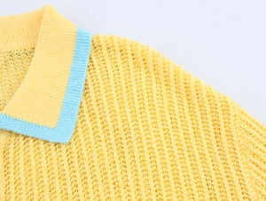 Détail du haut polo en tricot jaune évidé avec col bleu contrasté et maille filet