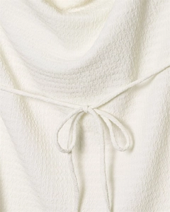 Detail of off-white textured fabric with bubble crepe finish and a tied ribbon bow