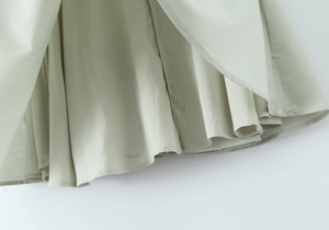 Détail de la robe vert sauge élégante montrant les coutures fines et le tissu en lin