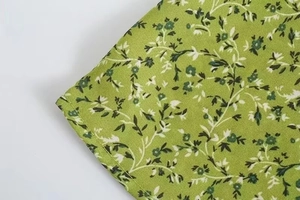 Close-up of green floral dress fabric featuring white blossom print and double stitching